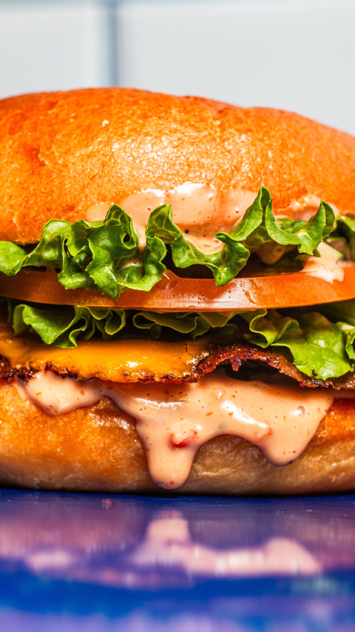 Close-up of a saucy cheeseburger with crisp lettuce and tomato